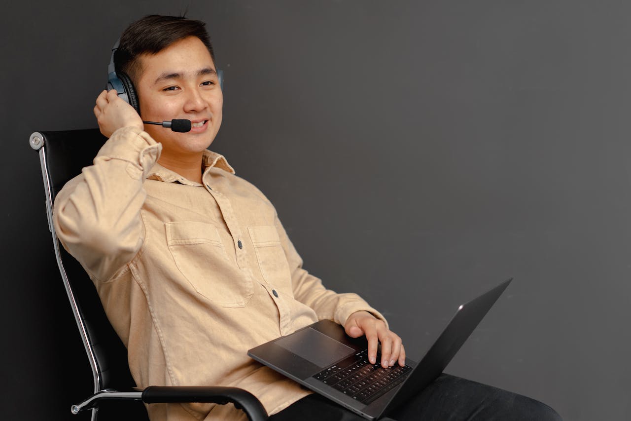 heros-img Smiling customer service agent using a laptop and headset indoors.